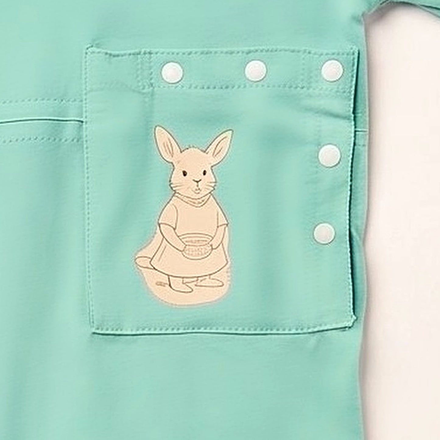 Close-up of the PediaPouch snap-close tube pocket with kangaroo detail on the Calm Mint bodysuit