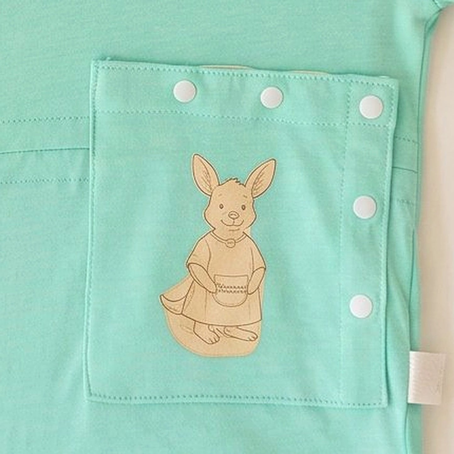 Close-up of the PediaPouch snap-close tube pocket with kangaroo detail on the TubeWear infant gown