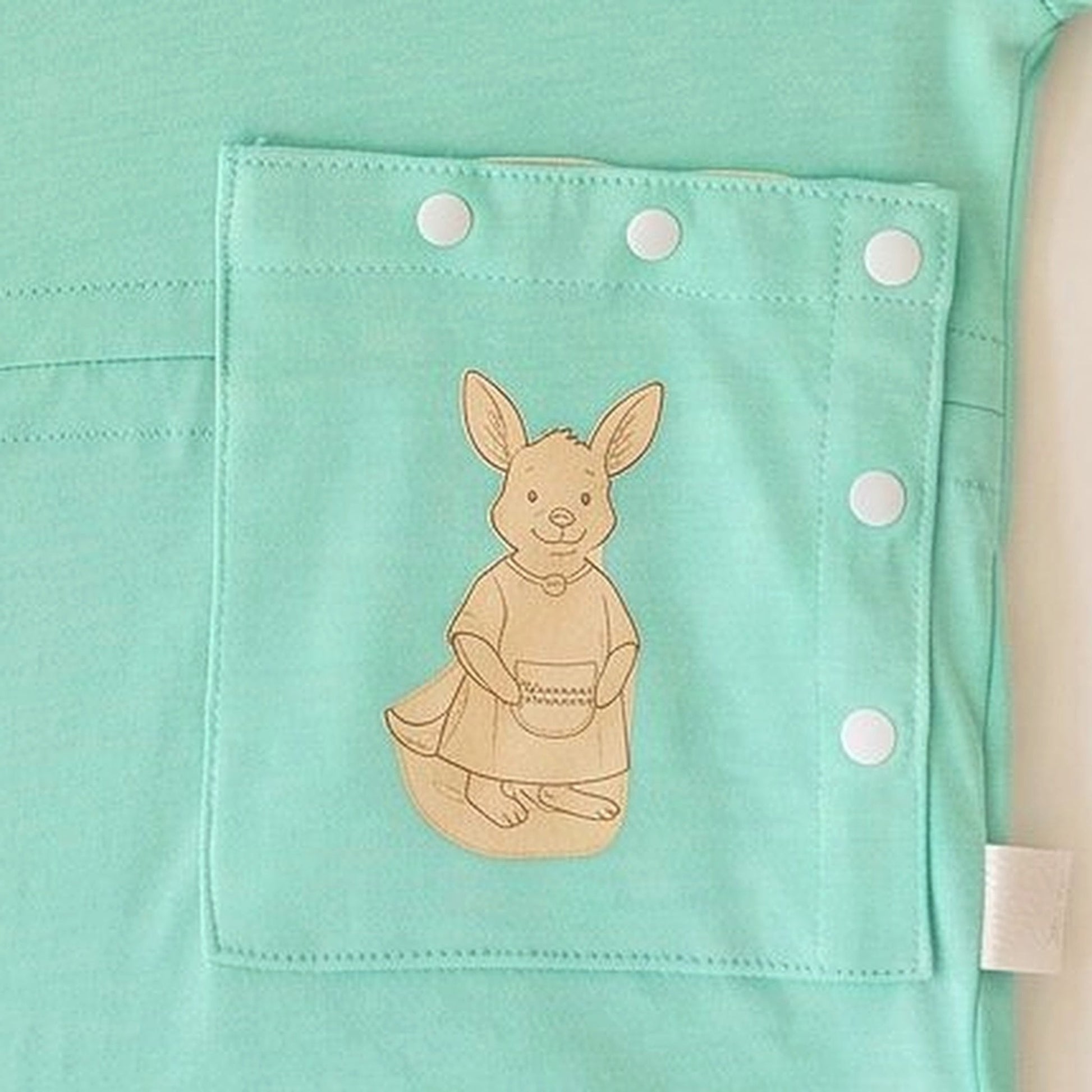 Close-up of the PediaPouch snap-close tube pocket with kangaroo detail on the TubeWear infant gown