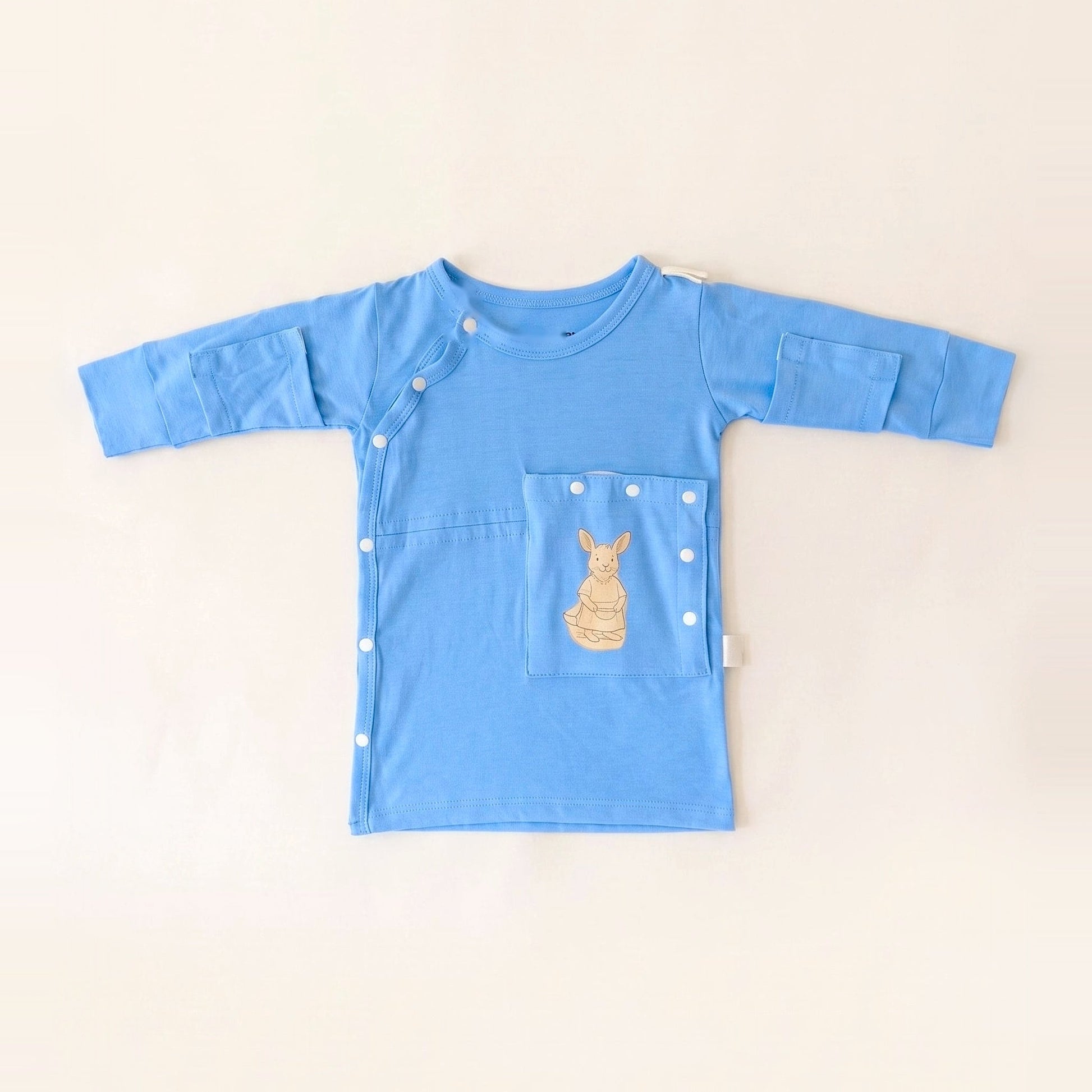 TubeWear adaptive G/J tube gown for newborns in Sky Lullaby blue, laid flat with the PediaPouch tube pocket closed
