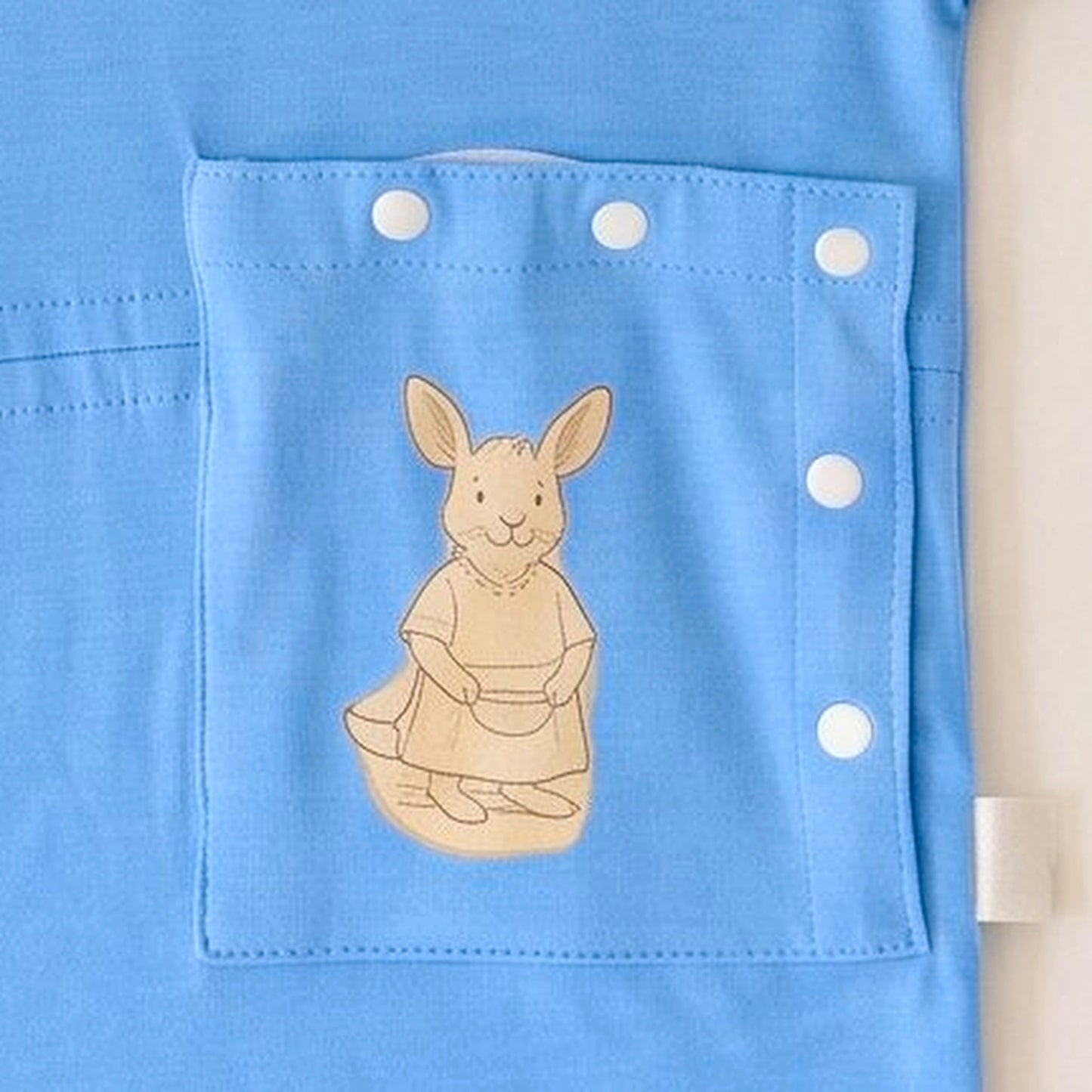 Close-up of the PediaPouch snap-close tube pocket with kangaroo detail on the Sky Lullaby infant gown